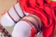 A close up of a person wearing a red dress and white stockings.