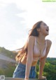 A woman in a pink bra top and blue jeans laughing.