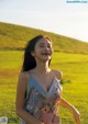 A woman in a floral dress standing in a field.