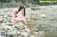 A woman in a pink kimono is standing in the water.