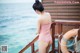 A woman in a pink bathing suit standing on a wooden deck.