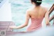 A woman in a pink dress standing on a wooden dock.