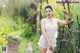 A woman in a white lingerie posing in a field of yellow flowers.