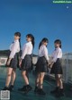 A group of young women standing next to each other on a bridge.