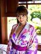 A woman in a purple and white kimono posing for a picture.