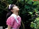 A woman in a pink dress standing in front of a bush.