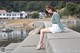 A woman sitting on a concrete wall by the water.