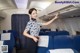 A woman in a blue and white uniform standing in an airplane.