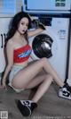 A woman sitting on the floor in front of a washing machine.