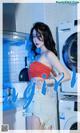 A woman standing in front of a washing machine in a kitchen.